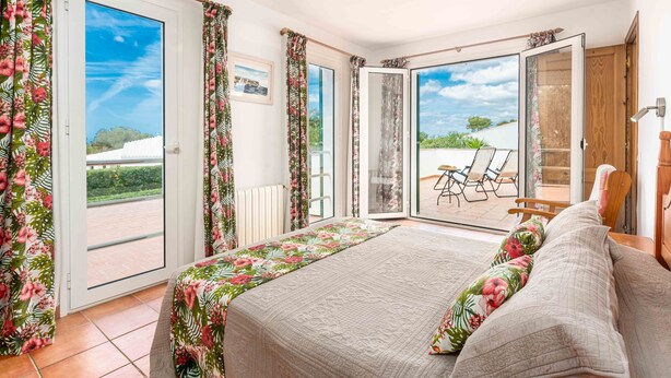 A bedroom with a bed, a view of the outdoors, and a sliding glass door. - Cosy detached villa with private pool near the beach (Binibequer)