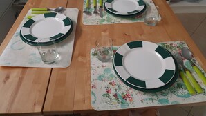 Een eettafel gedekt met borden, bestek en glazen, met een tafelkleed met bloemen.