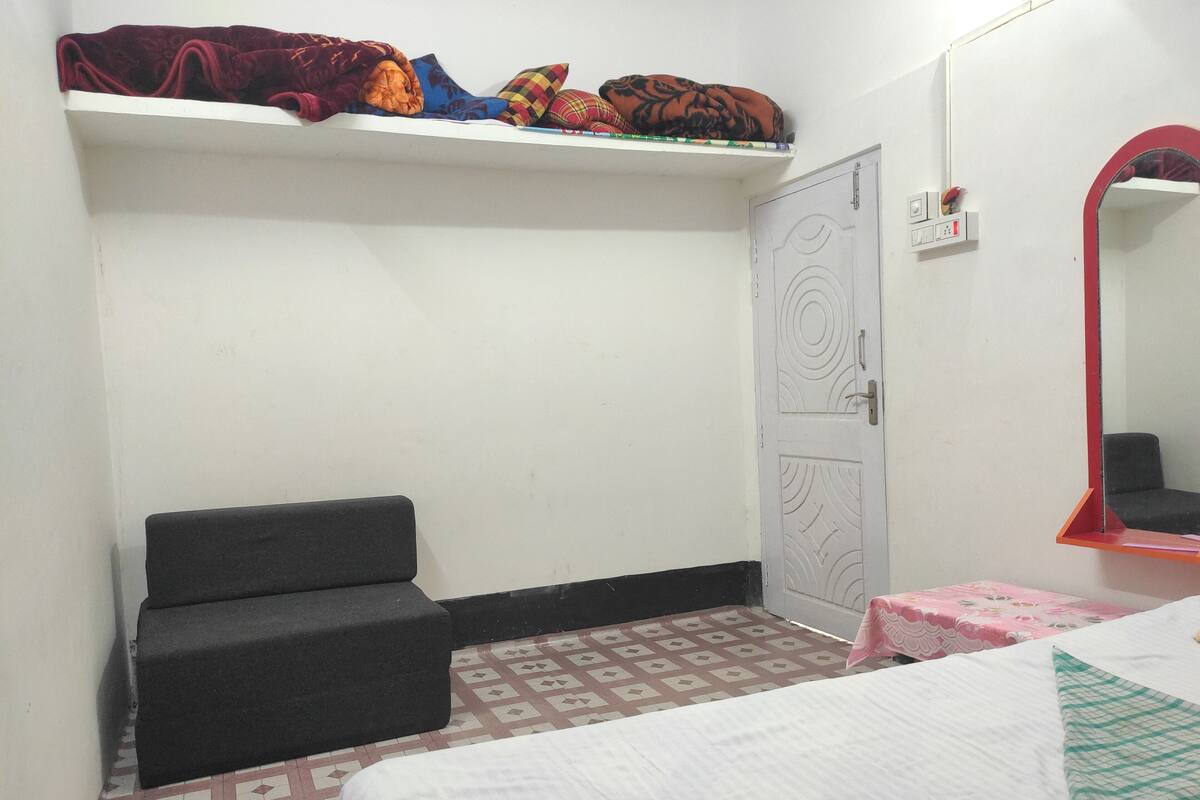 A bedroom with a bed, a sofa, a wardrobe, and a mirror.