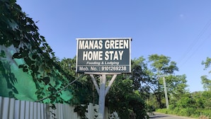 A sign for Manas Green Home Stay, indicating it offers food and lodging.