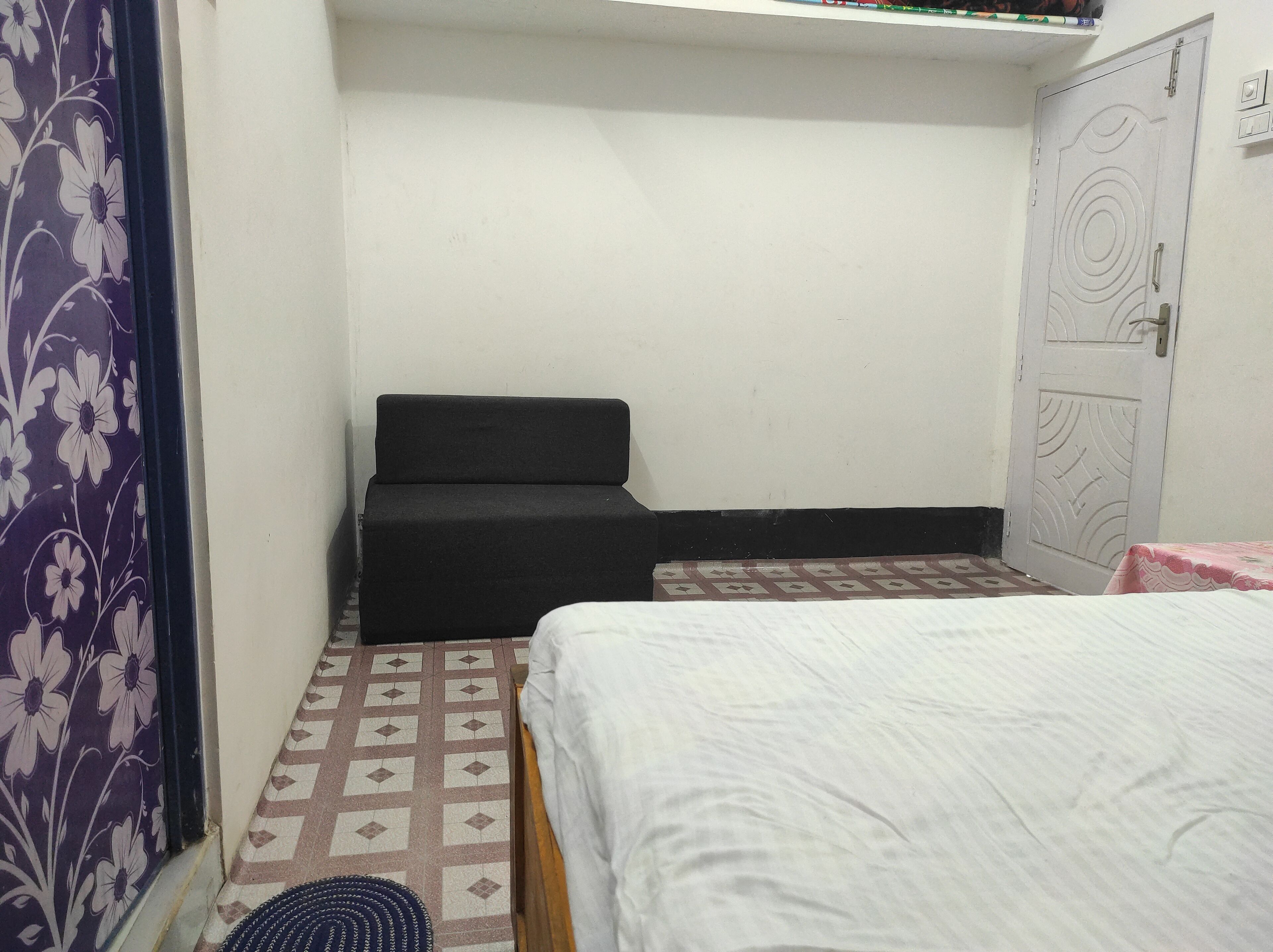 Una stanza piccola e modesta con un letto, un divano e una porta.