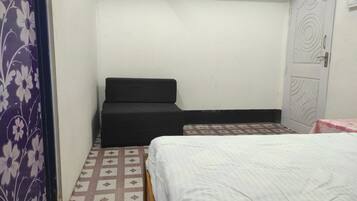 Una stanza piccola e modesta con un letto, un divano e una porta.