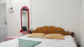 A bed with a wooden headboard, two pillows, and a green and white patterned blanket.