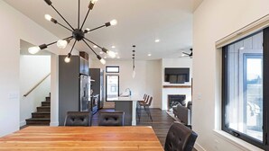 A modern kitchen with built-in appliances, a dining area with a wooden table and chairs, and a large window providing a view of the outdoors. - New 3 story home - Walking distance to the Milwaukee Trail and Good Food Store (Missoula)