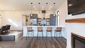 A modern kitchen with a central island, bar stools, and pendant lighting. - New 3 story home - Walking distance to the Milwaukee Trail and Good Food Store (Missoula)