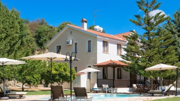 A two-story house with a swimming pool, surrounded by trees and outdoor seating. - Remarkable 5-bed Villa in Miliou Village Paphos (Miliou)