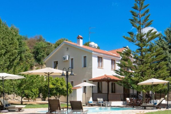A two-story house with a swimming pool, surrounded by trees and outdoor seating. - Remarkable 5-bed Villa in Miliou Village Paphos (Miliou)