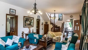 Amplia sala de estar con sofás color turquesa, una mesa de centro de madera y una escalera que sube a otro nivel.