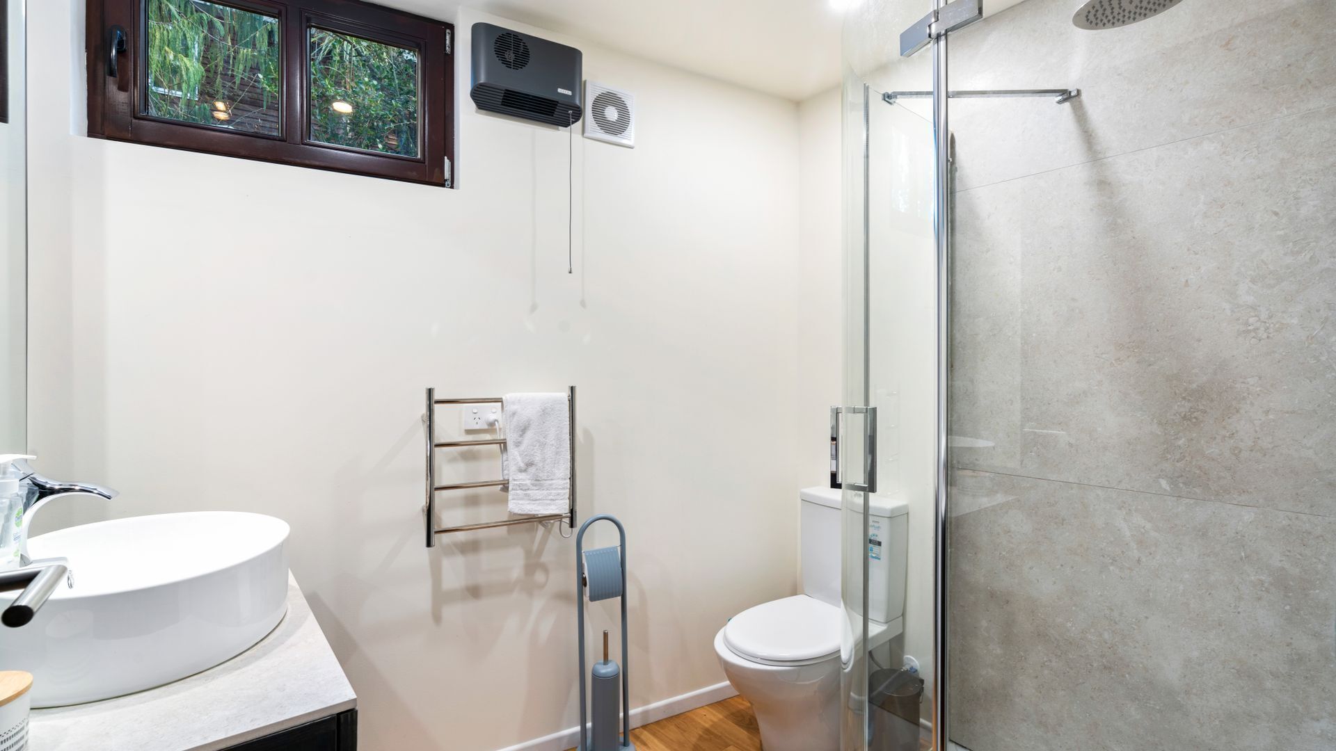 Un baño moderno con cabina de ducha de vidrio, un lavabo blanco y un inodoro.