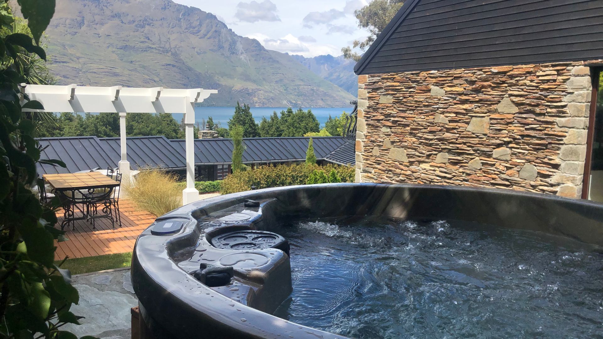 A hot tub with a stone wall and a view of mountains.