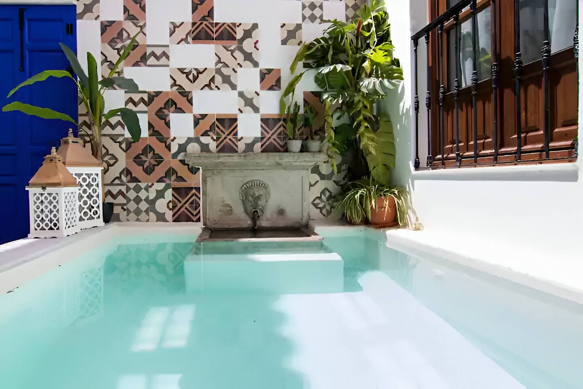 Una piscina con pared de azulejos y plantas en macetas.