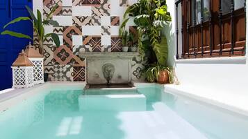 Una piscina con pared de azulejos y plantas en macetas.