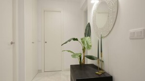A hallway with a white door, a black console table with a mirror and candles, and a plant. - Apartment Riad Alhambra 3 (granada)