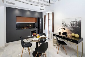 A modern kitchen with a dining area, featuring a black table, chairs, and a painting on the wall. - Riad Alhambra 3 (granada)