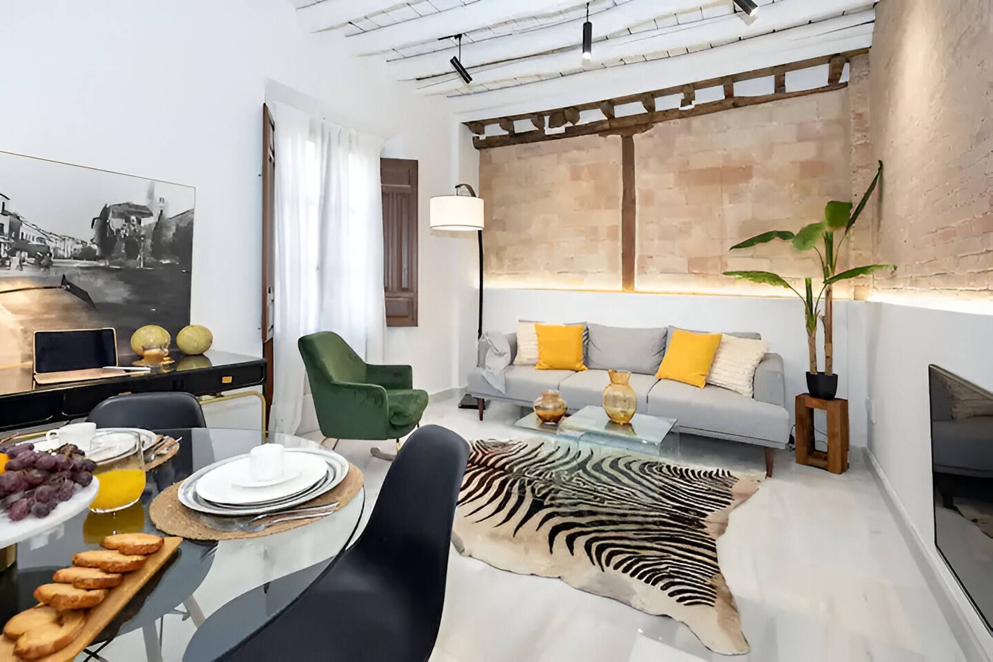 Una sala de estar moderna con un sofá, una mesa de comedor con platos y vasos, un alfombrado de cebra y una planta grande.