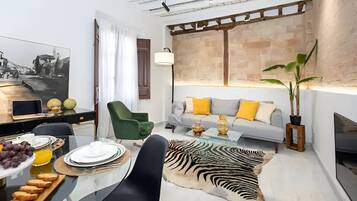 Una sala de estar moderna con un sofá, una mesa de comedor con platos y vasos, un alfombrado de cebra y una planta grande.