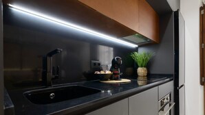A modern kitchen with a black countertop, stainless steel appliances, and a built-in oven. - Apartment Riad Alhambra 3 (granada)