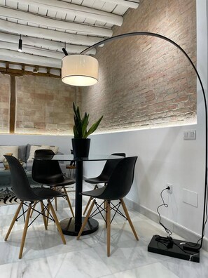 A dining area with a round table, four chairs, a floor lamp, and a potted plant.