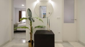 A hallway with a potted plant, a black pedestal, and a round mirror on the wall. - Apartment Riad Alhambra 3 (granada)