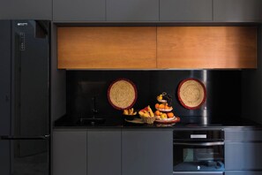 A modern kitchen with a built-in oven, a refrigerator, and a microwave.
