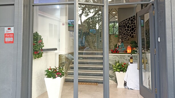 Entrada de un hotel con diseño moderno, una escalera que conduce al interior y un cartel que indica que es un albergue.