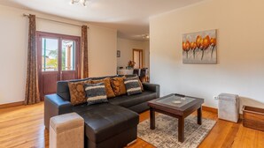 A living room with a sectional sofa, a coffee table, and a painting on the wall. - Villa Dinis (Calheta)
