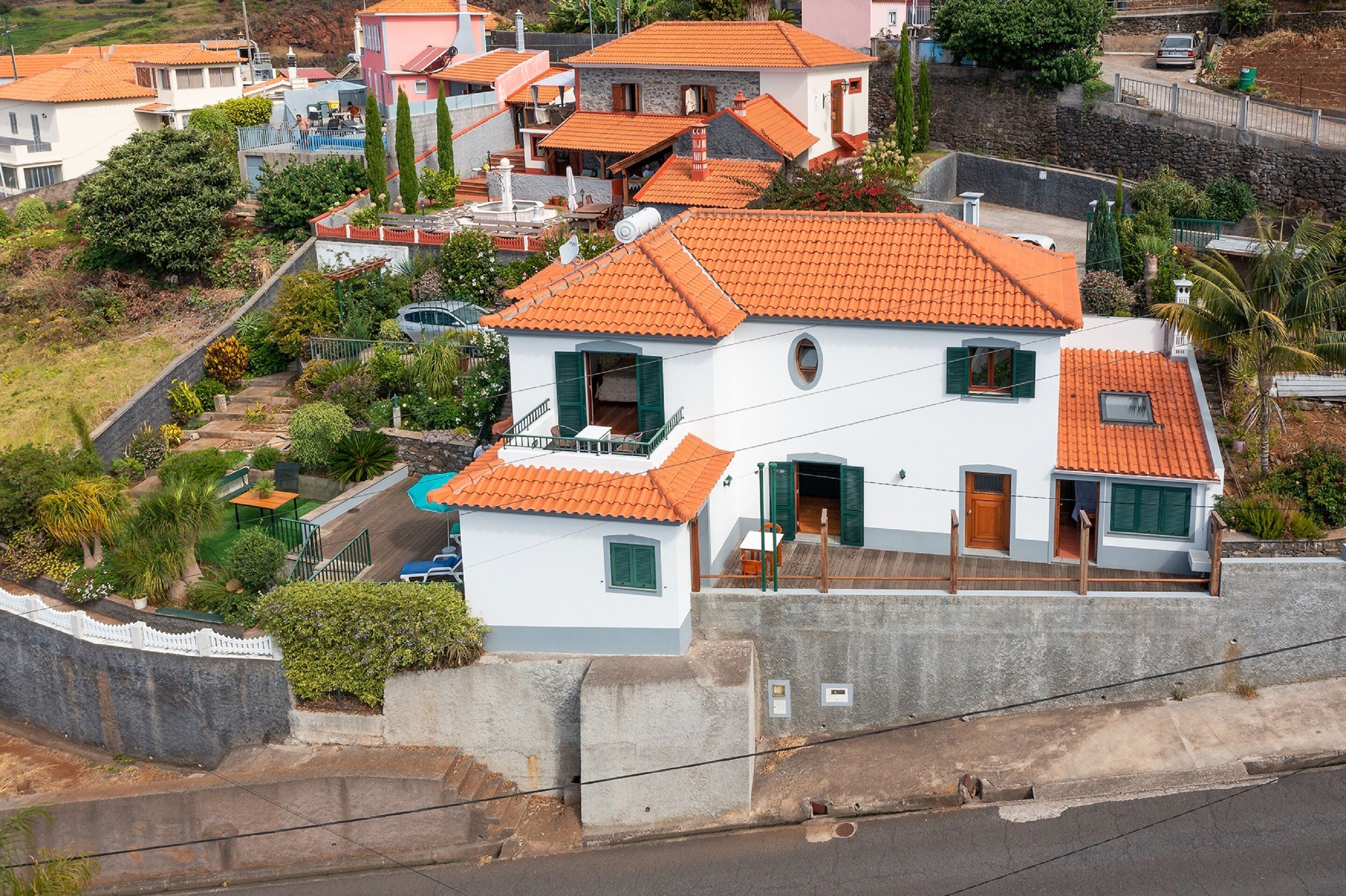 A residential building with a red-tiled roof, a swimming pool, and a white exterior.