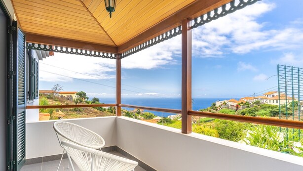 A balcony with a view of the sea and buildings. - Villa Dinis (Calheta)