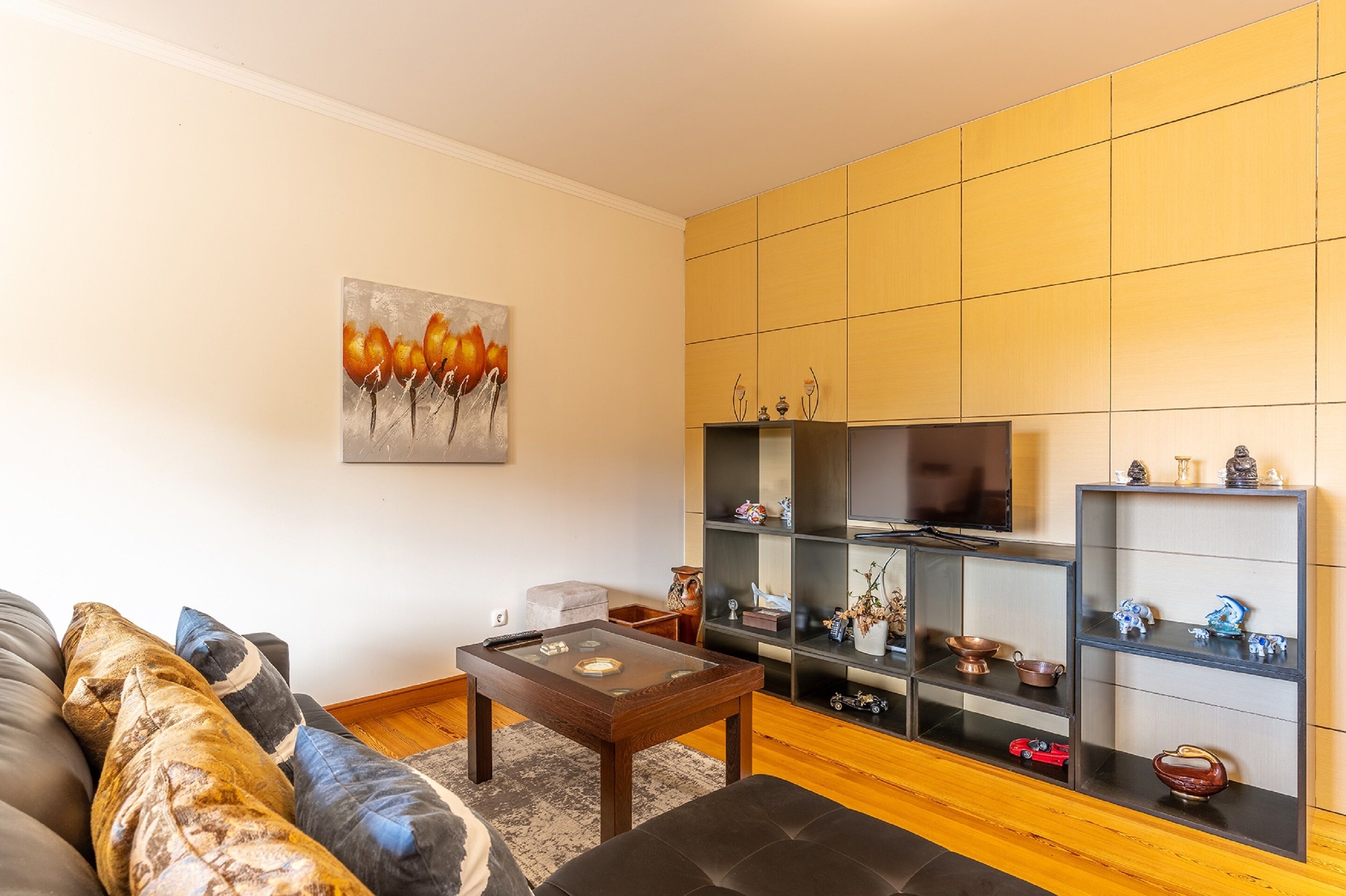 A modern living room with a sofa, a coffee table, and a TV stand with shelves.