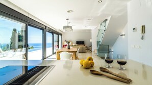 A modern kitchen with a large island, a dining area with a view, and a staircase leading to an upper level. - Villa La Perla with private heated pool and great views (Salobreña)