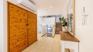 Un pasillo con puerta de madera, una escalera y una planta en maceta.