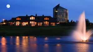 A large hotel with multiple buildings, a pond with a fountain, and a moon in the sky. - ⛳ The Loft Retreat @ Grand Traverse Resort | Golf Views, Balcony + Resort Perks ➠ 5549 (Acme)