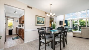A dining area with a table and chairs, a chandelier, a clock, and a painting on the wall. - ⛳ The Loft Retreat @ Grand Traverse Resort | Golf Views, Balcony + Resort Perks ➠ 5549 (Acme)