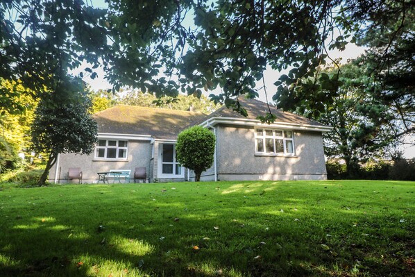 A two-story house with a well-maintained lawn and a small tree in front.
