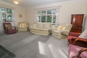 A living room with a beige sofa set, a wooden cabinet, and a red armchair.