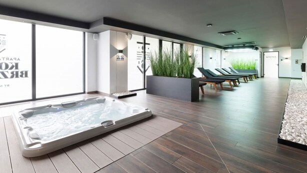A modern spa area with a hot tub, lounge chairs, and large windows.