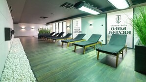 A modern waiting area with lounge chairs, a pebbled walkway, and a wall with signage.