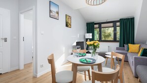 A modern living room with a dining table, chairs, a sofa, and a window with curtains.