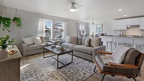 A modern living room with a sofa, coffee table, and a dining area with bar stools.