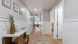 A hallway with a white console table, a bench, and a rug.