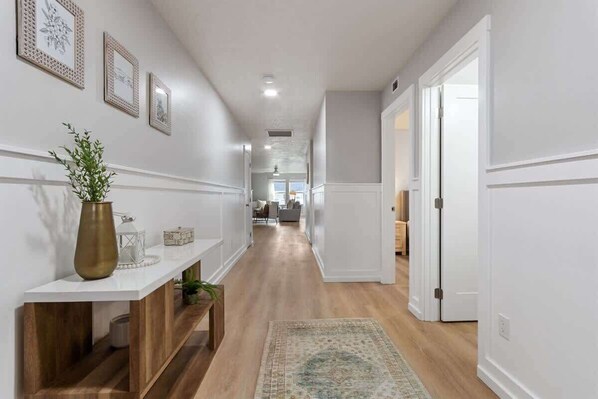 A hallway with a white console table, a bench, and a rug. - Cozy Costal Get Away | Meridian Idaho | 4 bedroom (Meridian)