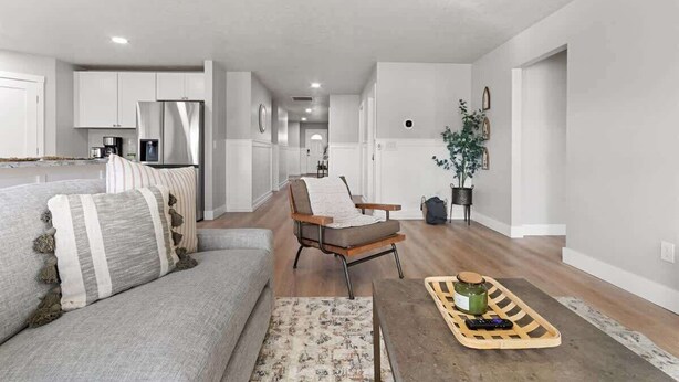 A modern living room with a sofa, armchair, coffee table, and a kitchen area in the background.