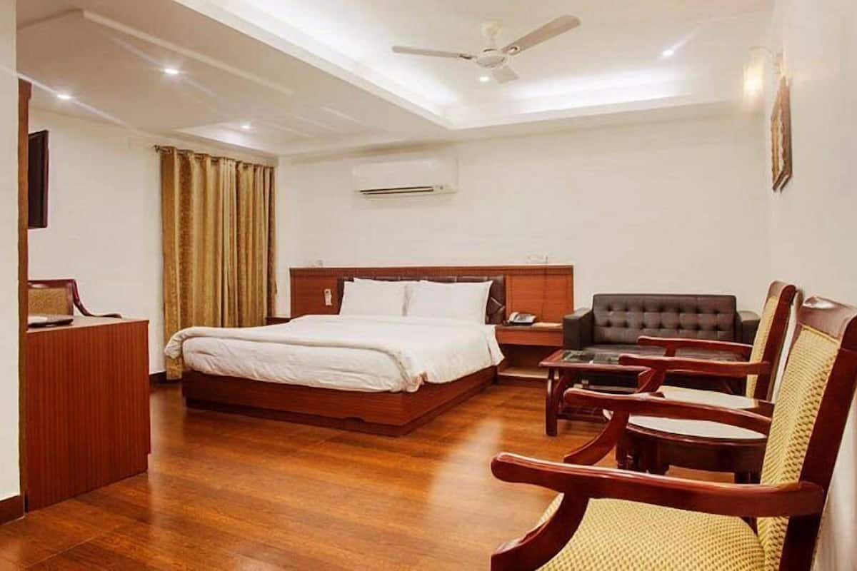 A hotel room with a bed, a desk, a chair, and a sofa.