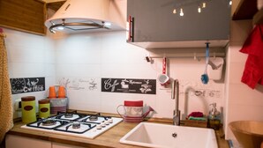 A kitchen with a gas stove, a sink, and various kitchen items.