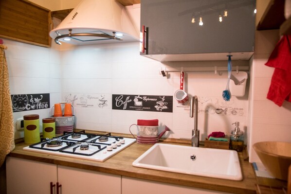 Une cuisine équipée d’une cuisinière à gaz, d’un évier et de divers ustensiles de cuisine.
