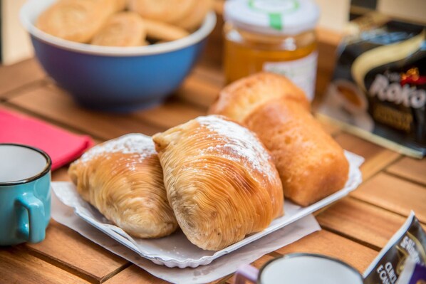 Een dienblad met croissants, een pot honing en een koffiemok op een houten tafel.
