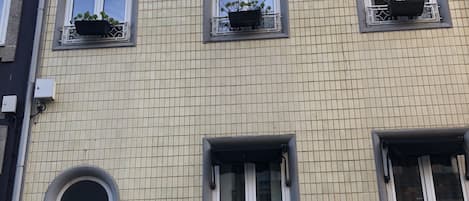 A multi-story building with a tiled facade, multiple windows with flower boxes, and a circular window.