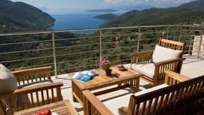 Una terraza de madera con una mesa, sillas y un cuenco de fruta.