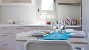 Una cocina moderna con armarios blancos, una mesa de comedor dispuesta con platos, vasos y un mantel individual azul.