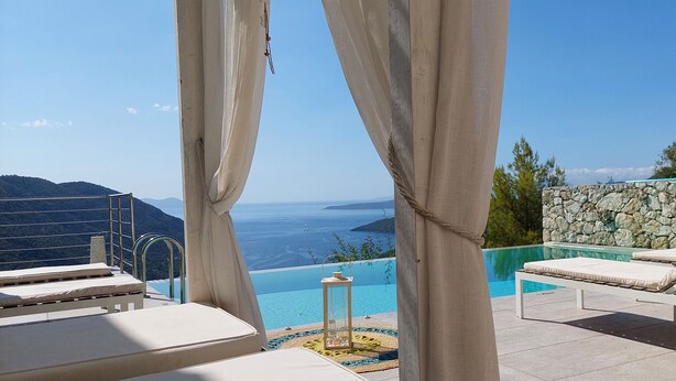 Zona de piscina con sillones y vista al mar.